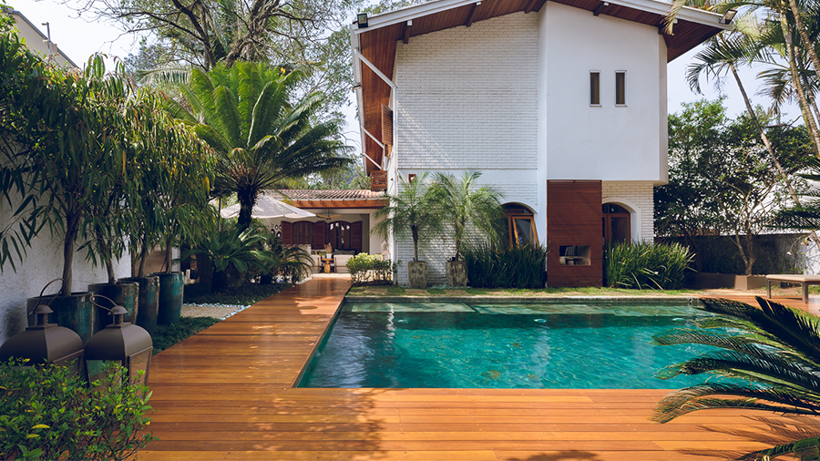 Parte exterior de residência,  piscina com deck de madeira cumaru e bastante planta ao redor