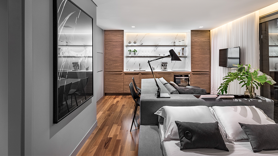 Sala com Home Office Integrado através de aparador de sofá, piso de madeira e decoração predominante em cinza.