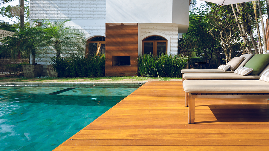 Área externa de uma casa com piscina e deck de madeira