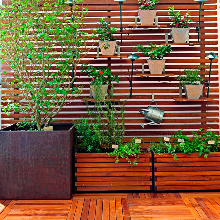 Fotografia de um painel ripado de madeira com vasos de plantas pendurados.