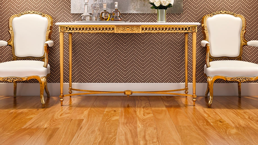 Fotografia de vista frontal de duas cadeiras, em couro branco e metal dourado, e de uma mesa dourada e branca. O chão é formado pela madeira Cumaru Assoalho. 