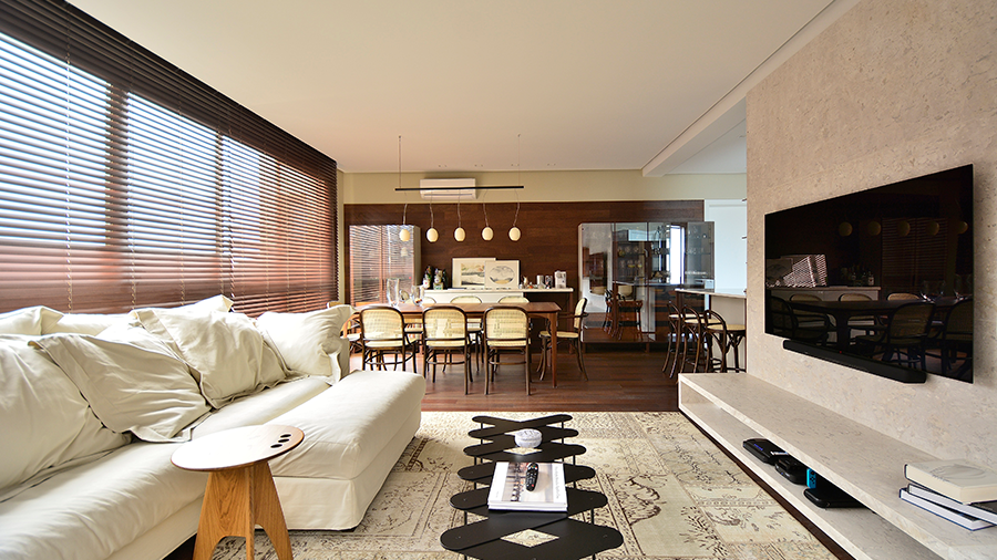 Fotografia de ambiente interno com sala de estar e sala de jantar, com a presença do Assoalho Multiestruturado Copaiba Pinot Noir Escovado e com decoração em branco e creme.