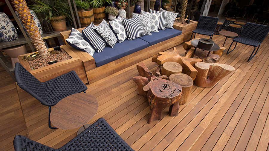Fotografia de área externa de casa com deck liso de cumaru e elementos da arquitetura tropical.