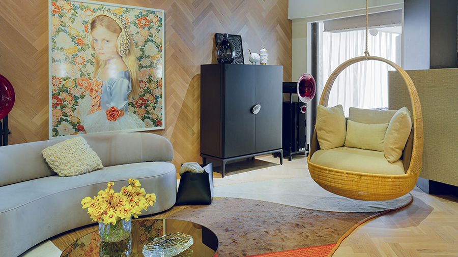 Fotografia de sala de estar com piso e revestimento de madeira, cadeira suspensa e itens de decoração.