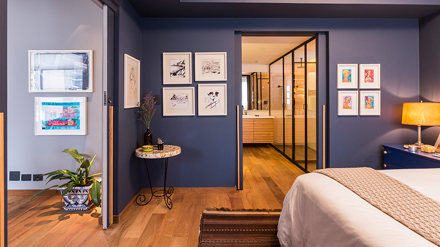 Fotografia de quarto com piso de madeira, parede azul e itens de decoração em tons nude.
