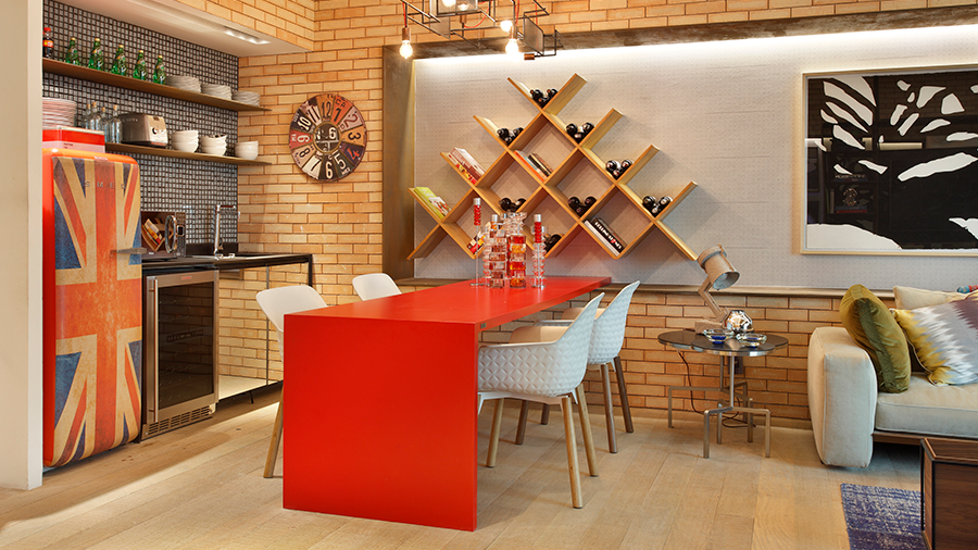 Fotografia de uma cozinha com paredes de tijolinho, piso de madeira, além de móveis e eletrodomésticos vermelhos