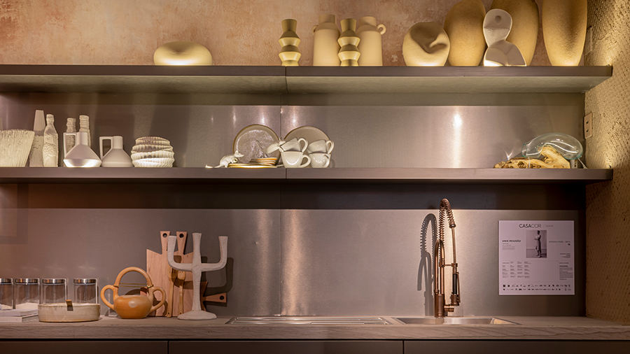 Fotografia de uma bancada de cozinha com acessórios de cerâmica e de madeira bruta.