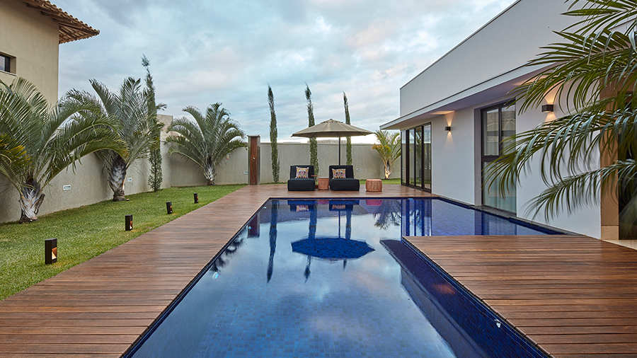 Fotografia de uma área externa com deck de madeira e piscina. 