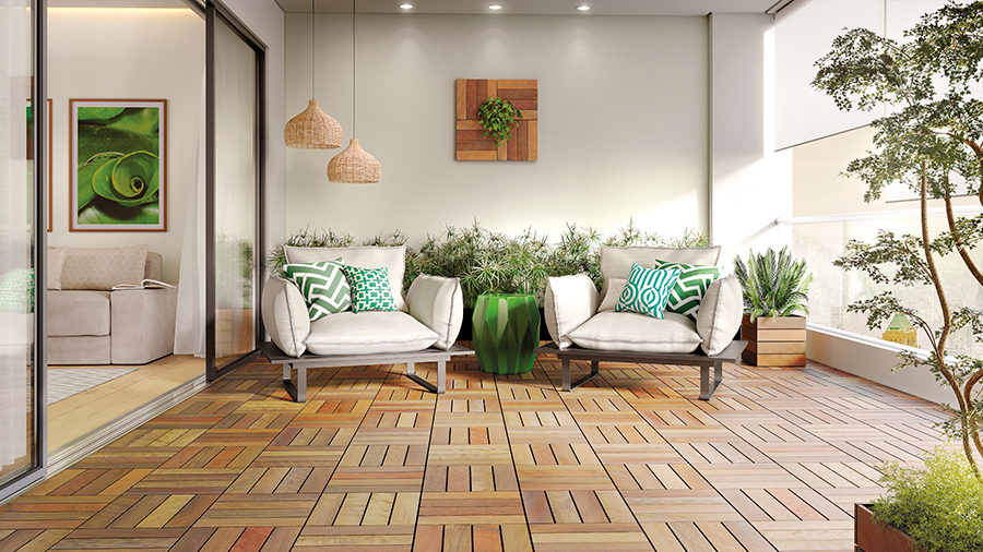 Fotografia de uma área interna com deck de madeira modular, plantas, poltronas e acessórios em tons de verde.