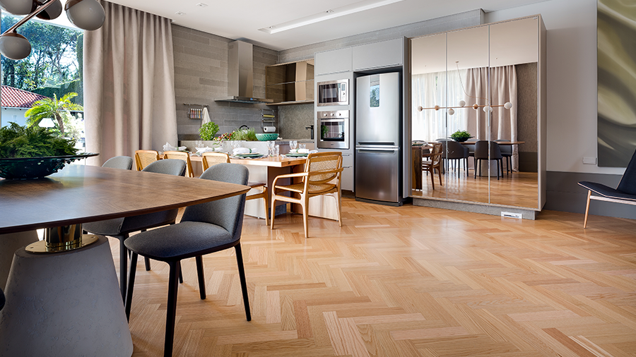 Fotografia de um espaço interno de cozinha integrada com piso de madeira clara.