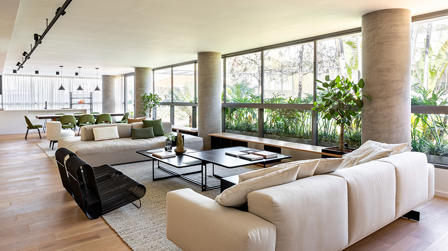  Fotografia de um ambiente interno com janelas grandes, móveis de sala de estar e piso de madeira.