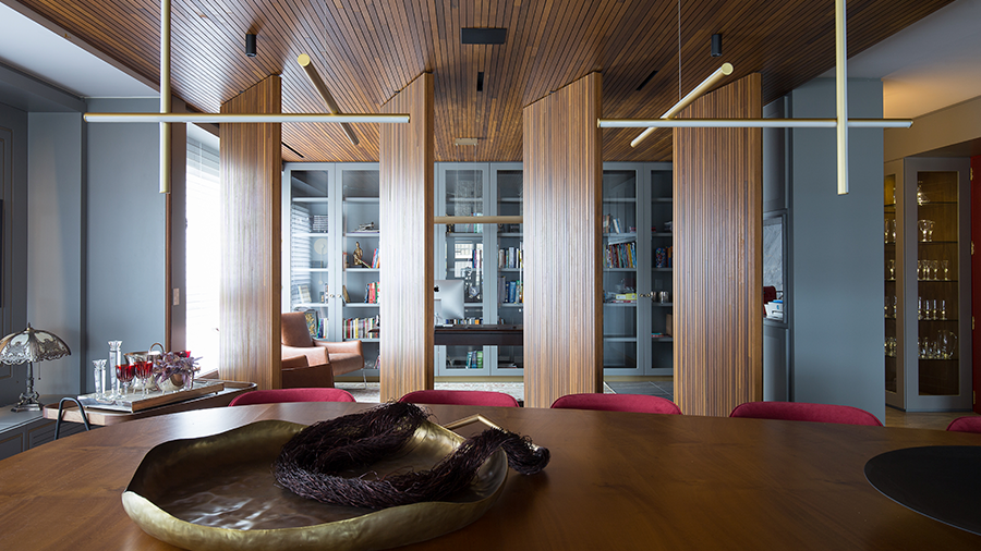Fotografia de um espaço interno divido por brise de madeira.