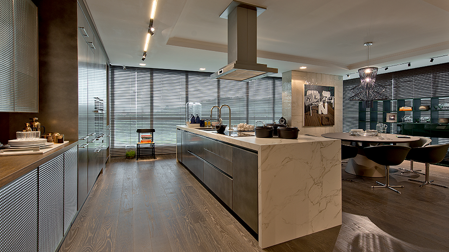 Fotografia de um espaço interno com piso de madeira, bancada de mármore e utensílios de cozinha.