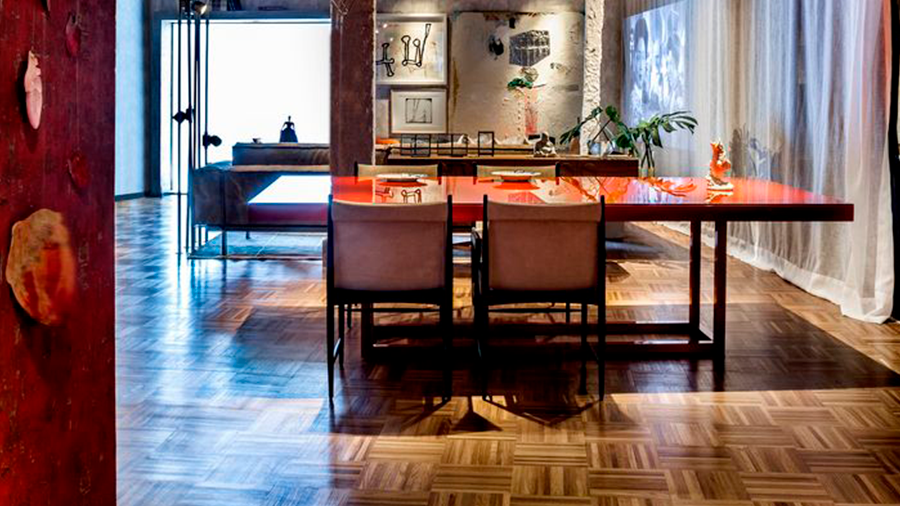 sala de jantar aberta com mesa central e detalhes em vermelho. 
