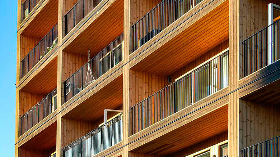 Imagem de um prédio com estrutura de madeira com sacada e janelas.