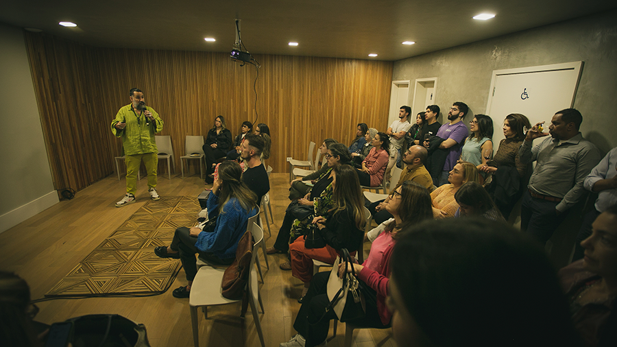 Fotografia de Pedro Franco apresentando o desenho de um piso de madeira para uma plateia de pessoas.