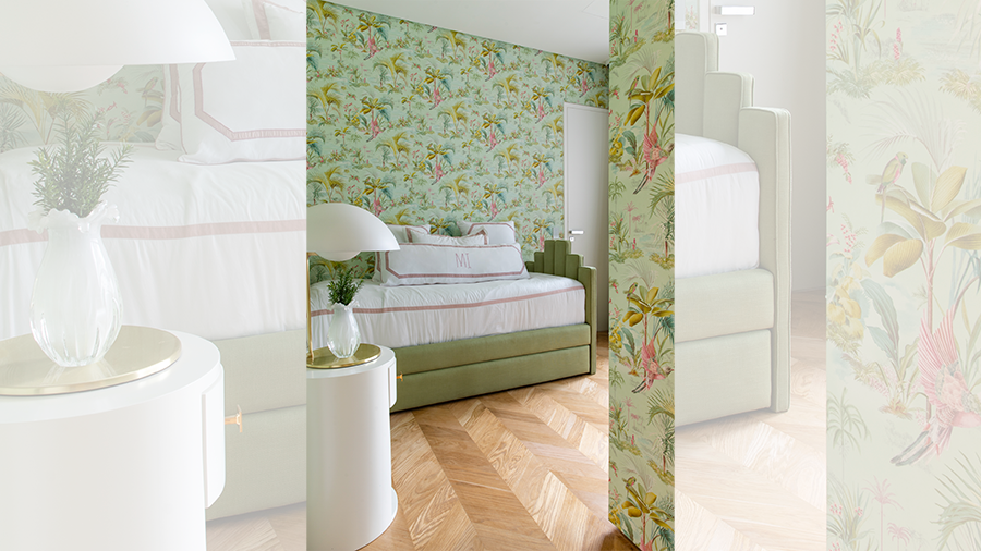Fotografia de um espaço interno com piso de madeira, cama de solteiro, papel de parede verde com estampa, mesa de apoio e luminária.