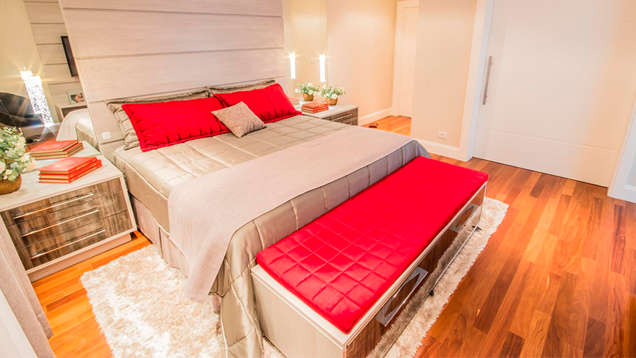 Fotografia de um espaço interno com piso de madeira, cama de casal, móveis e objetos de decoração