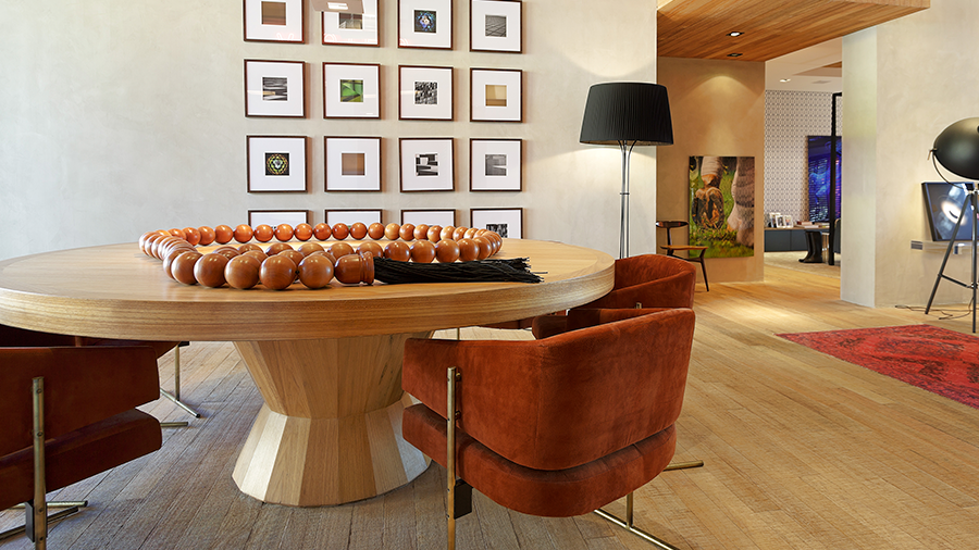 Ambiente com piso de madeira, mesa redonda espaçosa em madeira e decoração em tons de marrom por todo o ambiente