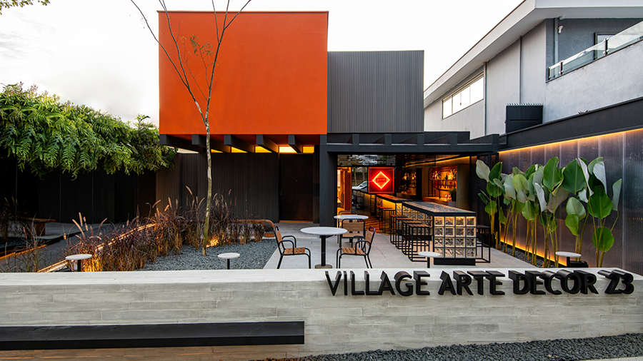  Imagem externa do Village Art Decor com mesas, cadeiras, árvore e plantas. Ao fundo, o espaço do evento.