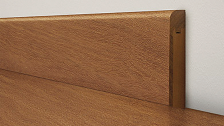 Imagem de um piso de madeira e um rodapé de madeira multristato em uma parede clara.