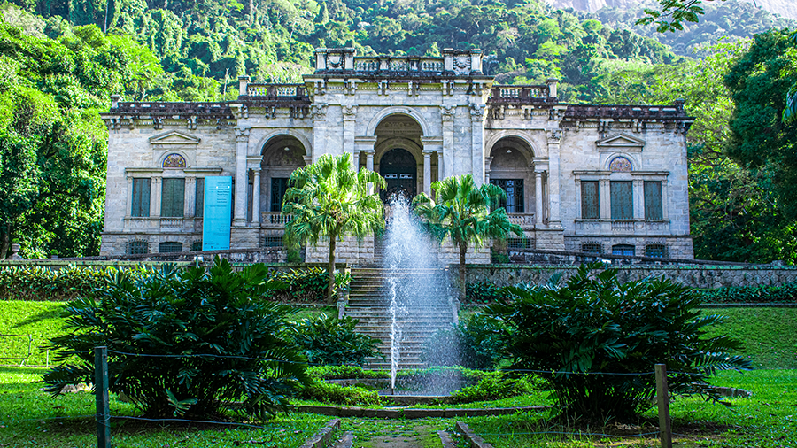 Foto externa do Parque Henrique Lage repleto de área verde ao redor e uma fonte no centro da imagem