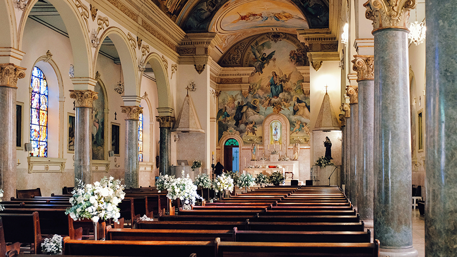  Interior da Igreja Nossa Sra. do Rosário, com bancos de madeira escura, paredes e forro com pinturas decorativas e as colunas têm pintura em escaiola