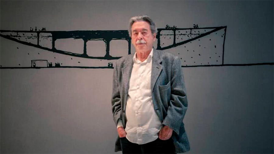 Foto do arquiteto Paulo Mendes da Rocha em frente a uma parede com uma obra de arte